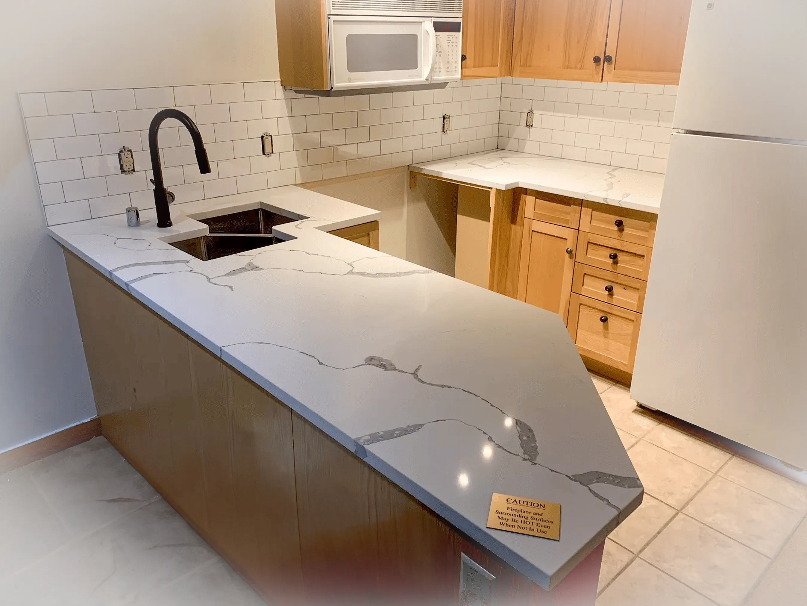 L-shaped kitchen with wood cabinets and bold marble-patterned quartz