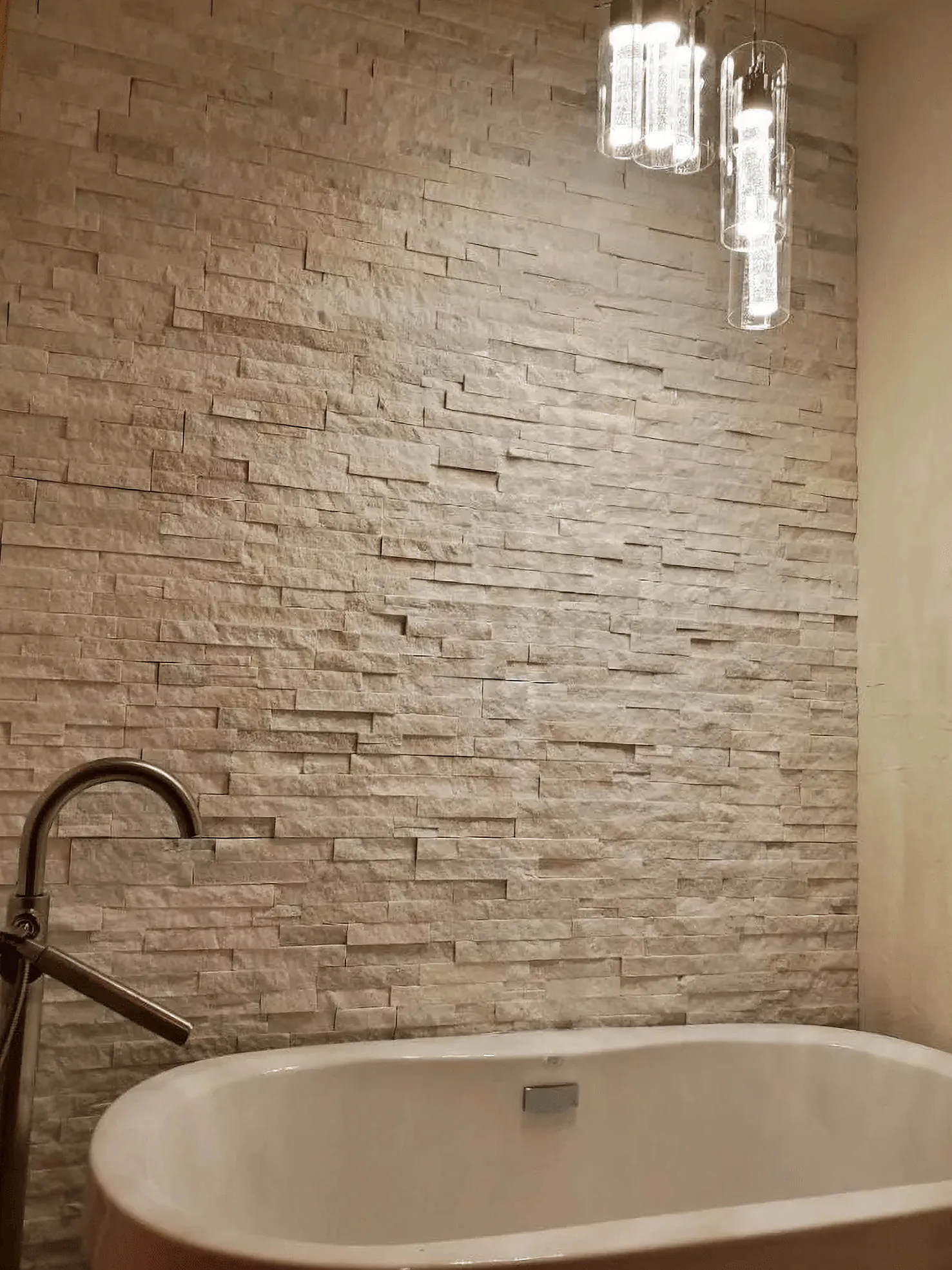 Master suite featuring a freestanding tub and stacked stone accent wall
