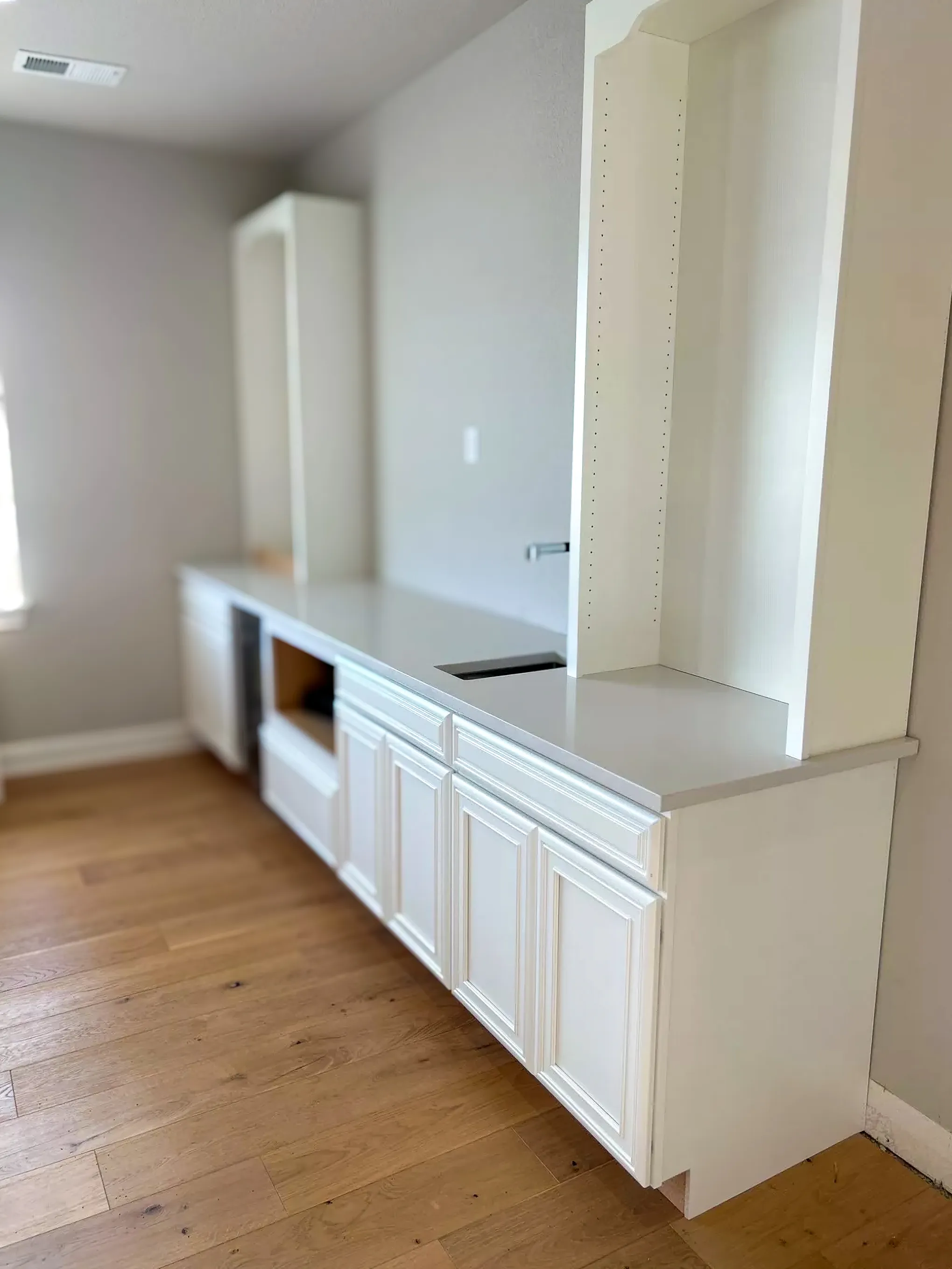 Modern bar area with white cabinetry and light quartz